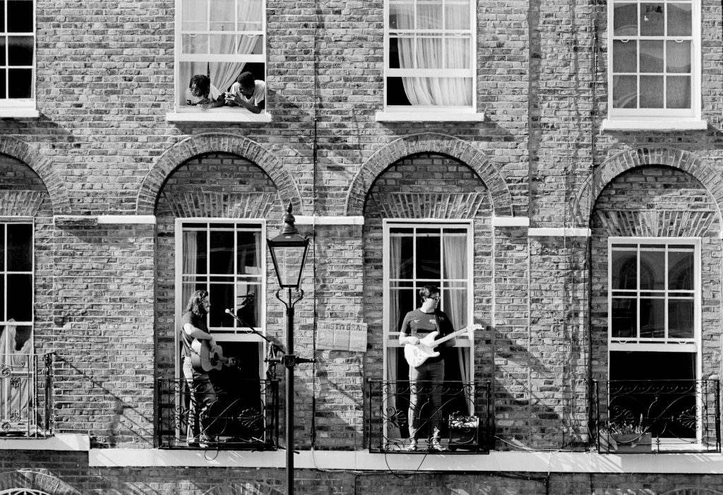 Boys playing guitar outside old houses