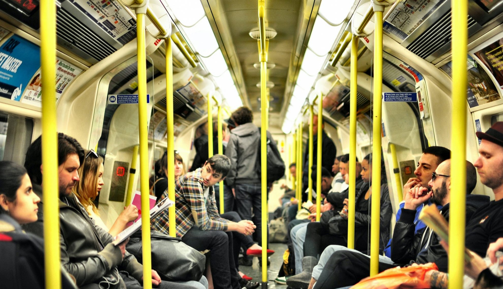 A busy London Underground tube carriage with yellow poles