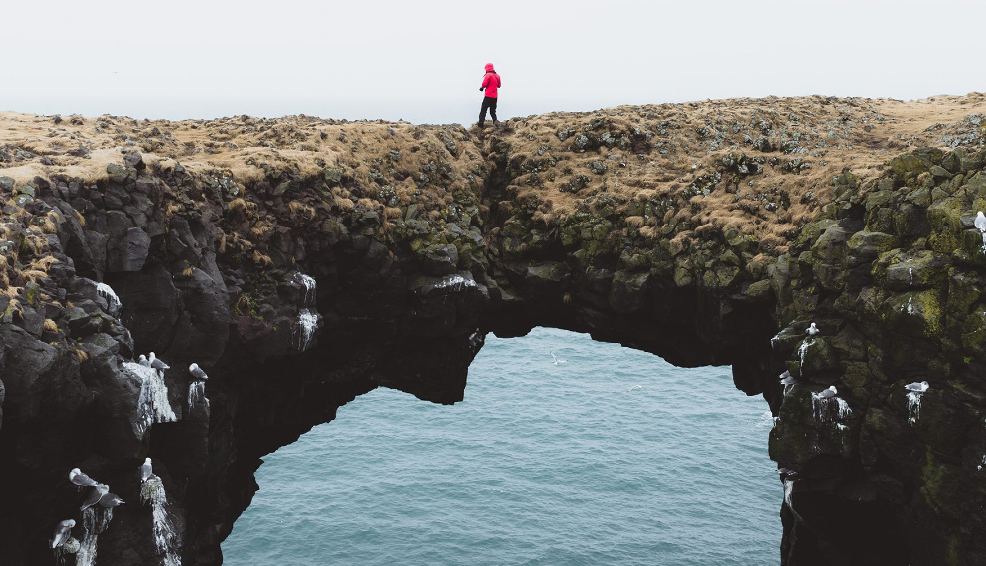 person walking over a natural rock bridge