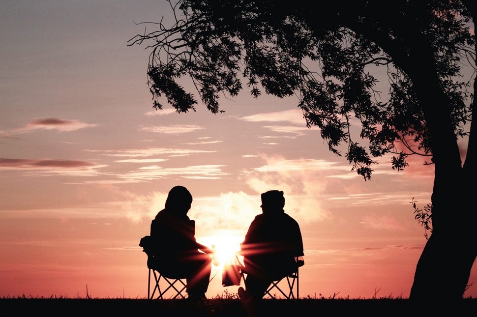 retired couple sitting watching the sun set