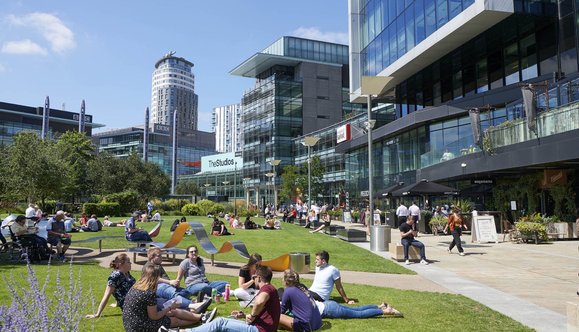 People sitting on the grass in MediaCity, Salford Quays