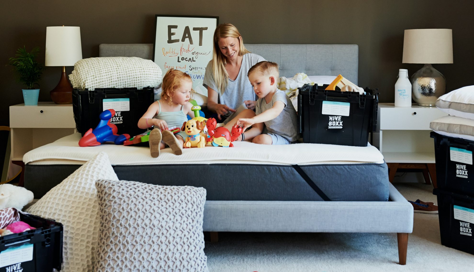 Woman and children on a bed surrounded by moving boxes