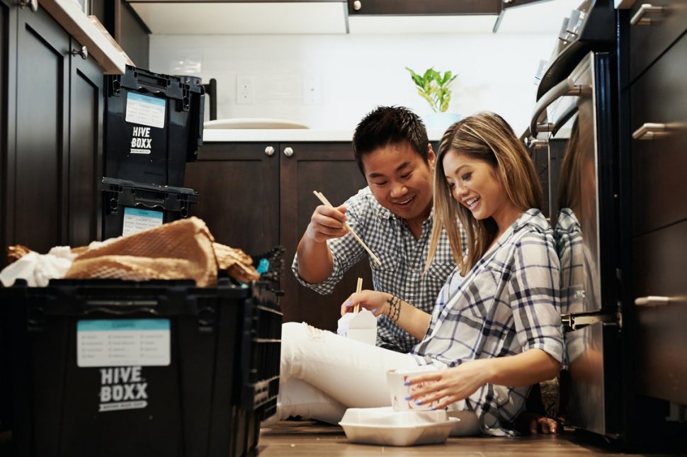 Asian couple eating Chinese food surrounded by moving boxes